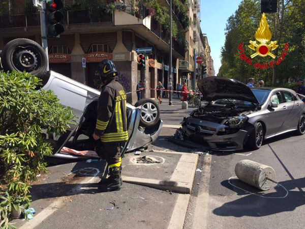 Scontro stradale con automobilista che si ribalta sul marciapiede