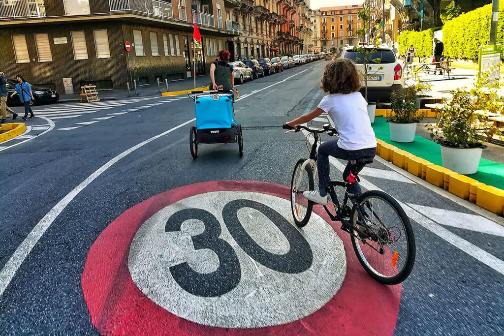 Pittogramma 30 e ciclisti in carreggiata durante un intervento di urbanistica tattica a Milano, quartiere Rovereto